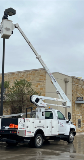 Cross Electric LLC tech repair a parking lot light.